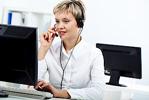 Frau vor Computer beantwortet Anruf über Headset