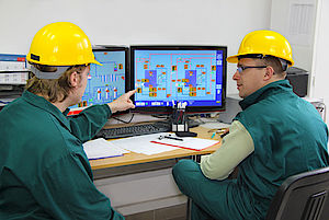Zwei Arbeiter vor Bildschirmen besprechen sich